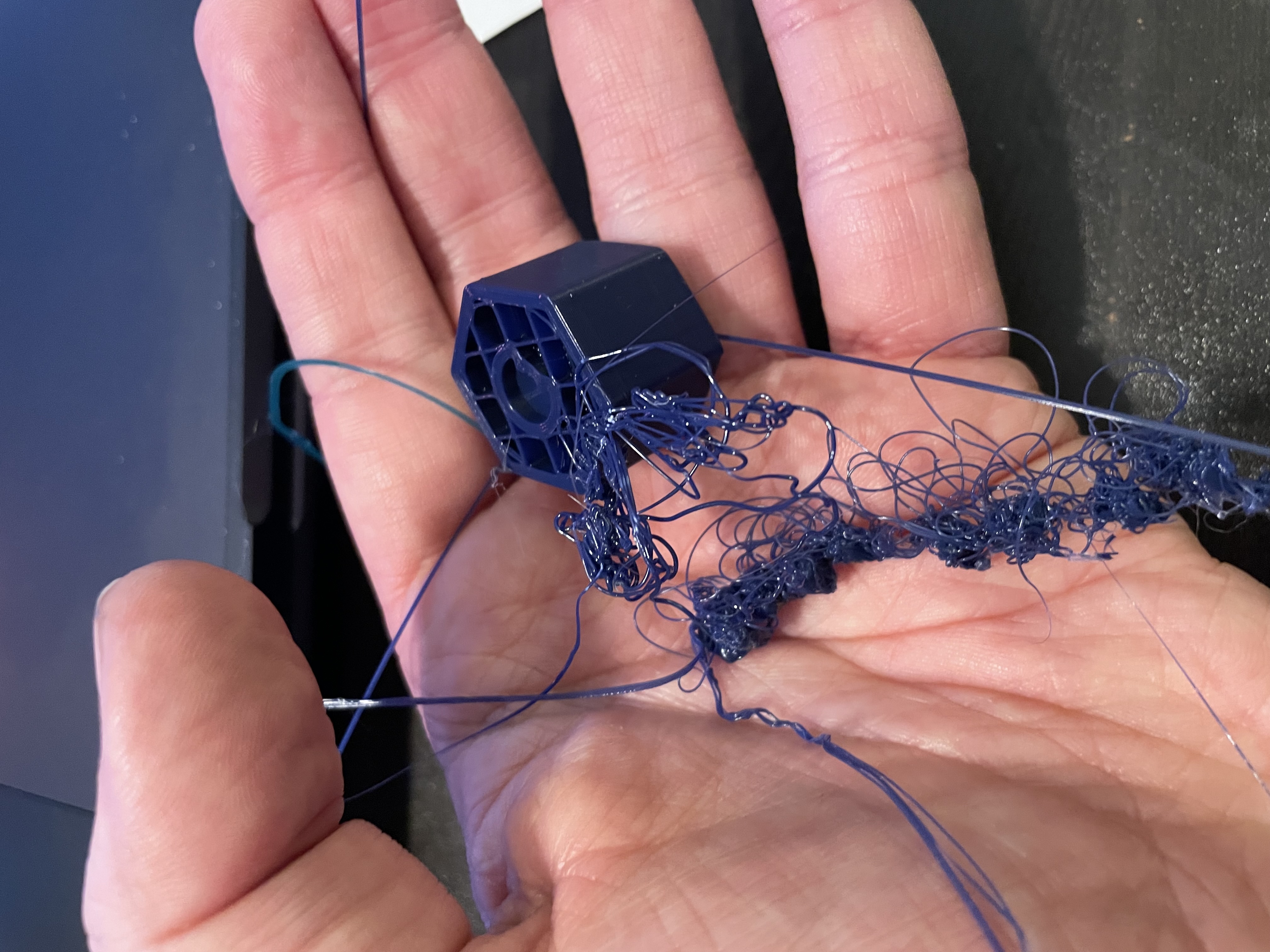 The first failed print — the hexagonal form and C groove are recognisable, but the rest is loose filament